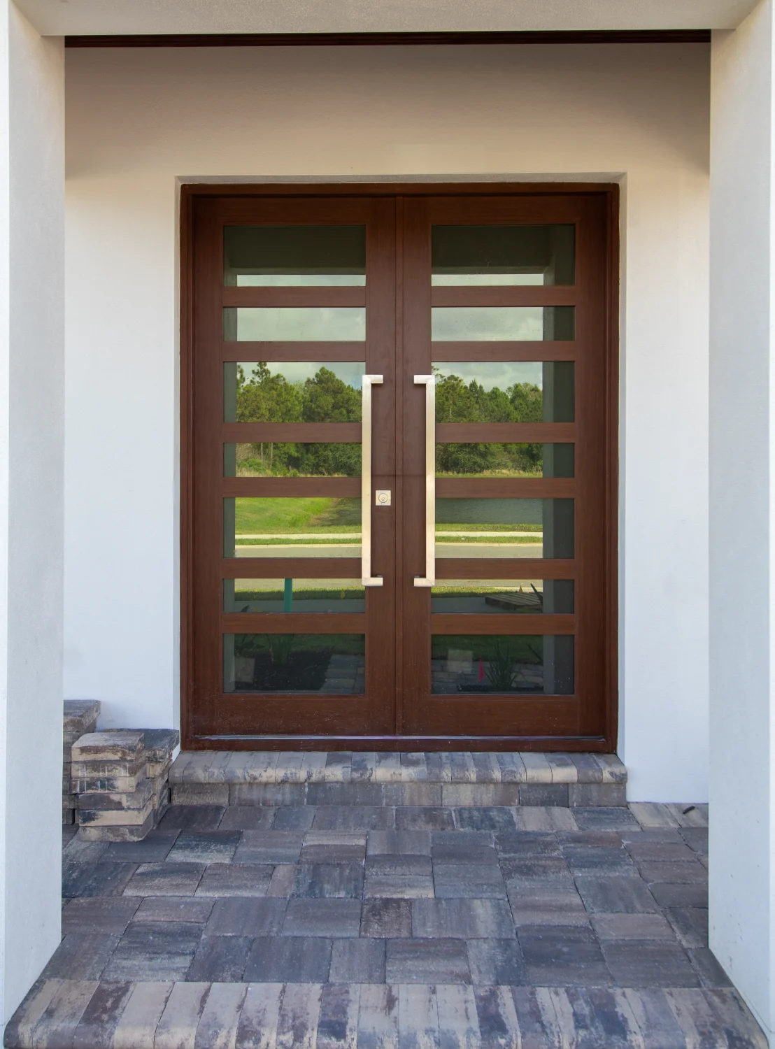 A double front door, made of wood, glass, and metal, on a luxury home. Installed by Freedom Windows & Doors