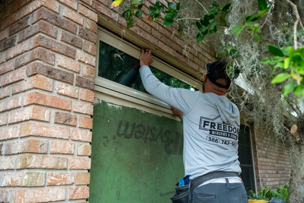 One of the owners of Freedom Windows & Doors installing a replacement window on a home