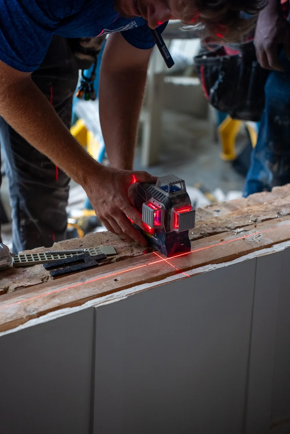A Freedom Windows & Doors installer using a laser-precise tool carefully measuring and preparing an opening for a window replacement