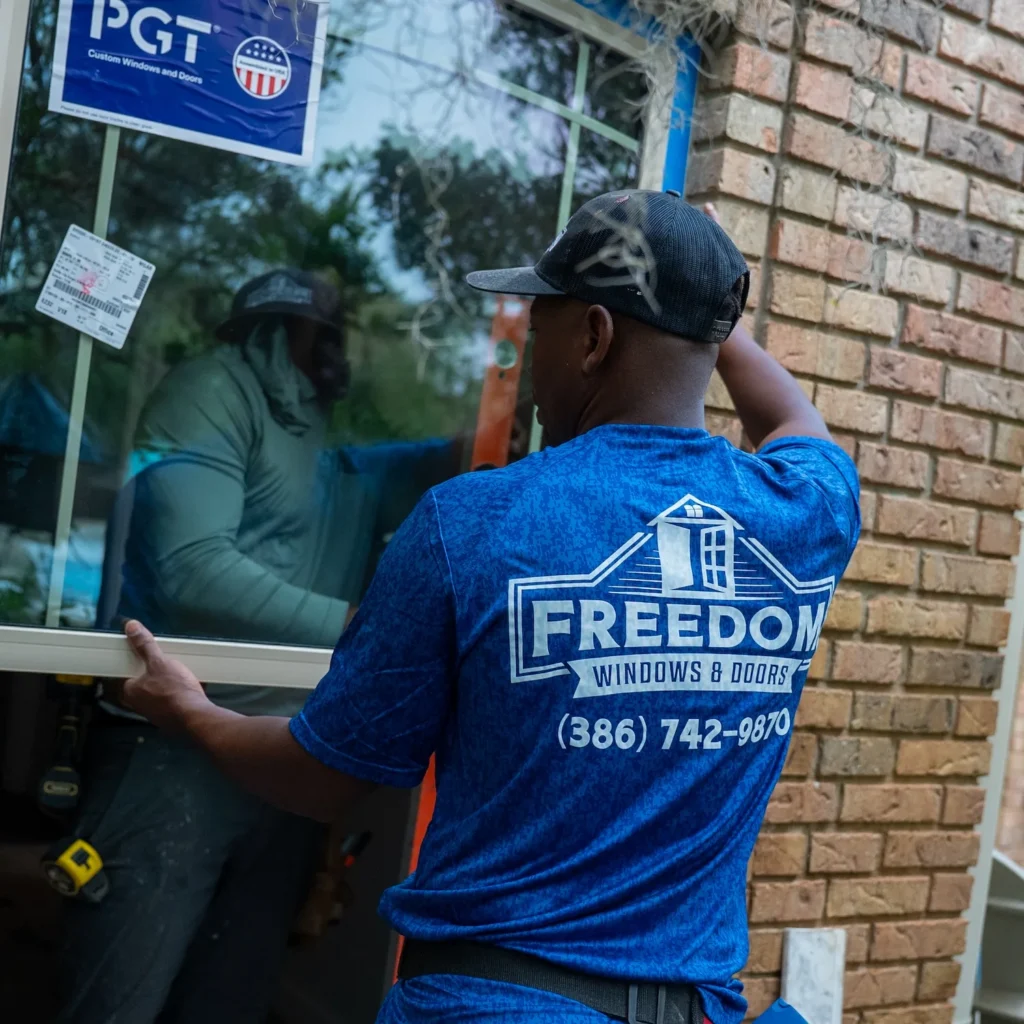 A Freedom Windows & Doors expert installing a PGT custom window on a high-end Florida home