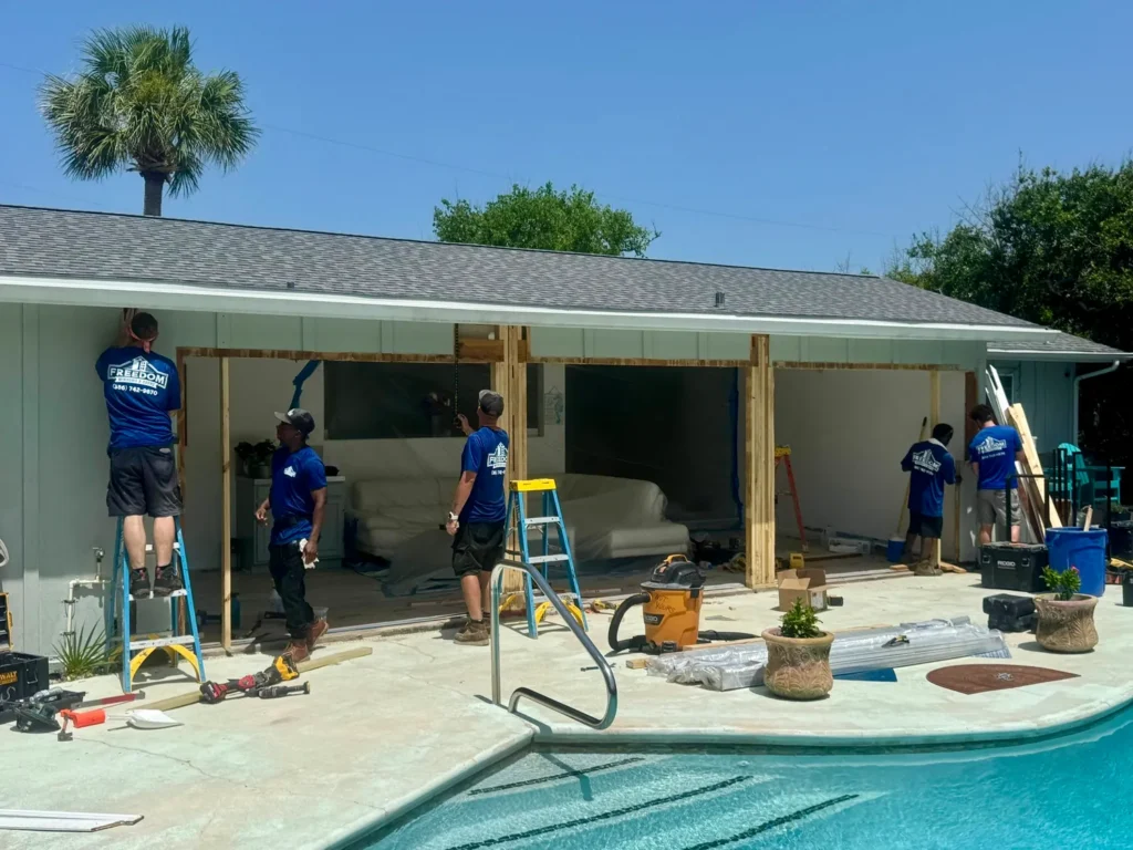 Freedom Windows & Doors professional crew replacing 3 sliding glass doors leading to a pool at a customer's home
